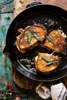 two grilled meats in a skillet on a wooden table next to flowers