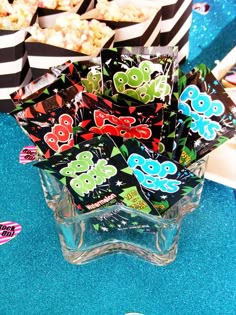 there are many candy bags in the glass vases on the blue tablecloth with black and white stripes