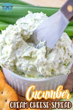 a white bowl filled with cucumber dip surrounded by crackers and celery