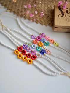 multicolored beaded necklace next to wooden box and straw basket on white surface