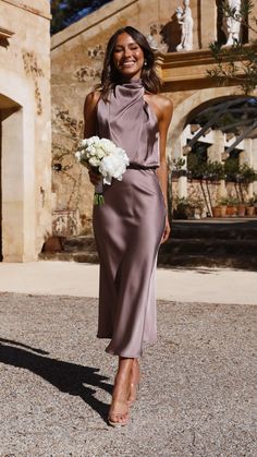 a woman in a purple dress holding a white bouquet