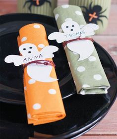 two halloween napkins on a black plate with orange and green paper wrapped around them