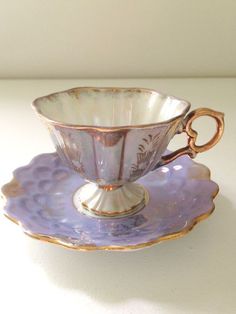 a purple cup and saucer sitting on top of a white table