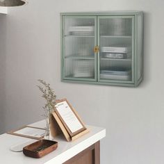 a white table with a book and some plants on it next to a green cabinet