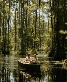 two people in a boat on a river surrounded by trees