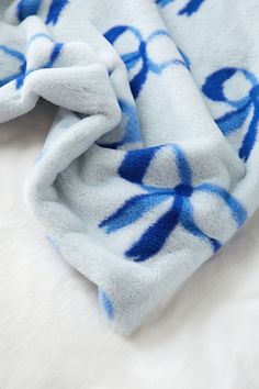 a blue and white blanket laying on top of a bed next to a stuffed animal