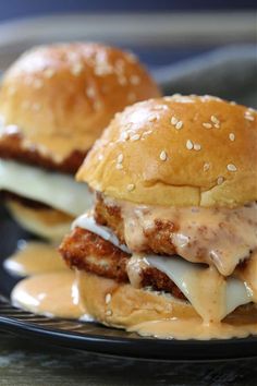 two burgers with cheese and sauce on a plate