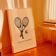 two tennis racquets on a table next to a framed game set match poster