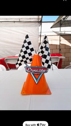 an orange traffic cone sitting on top of a white table covered in checkered flags