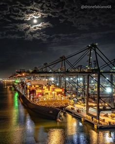 a large ship docked at night with the moon in the sky over it's horizon