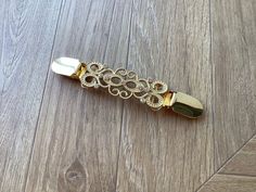 a gold and silver hair clip on a wooden floor