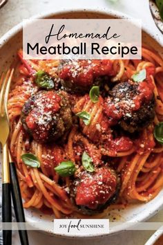 homemade meatball recipe in a white bowl with spaghetti and basil on the side next to two forks