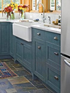 a kitchen with blue cabinets and tile flooring, white sink and dishwasher