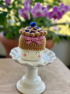 a small crocheted hat on top of a cake plate