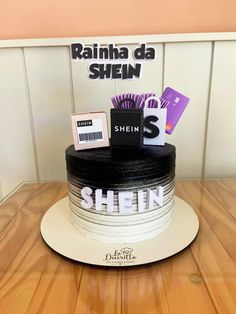 there is a black and white cake with the name shein on it, sitting on a wooden table