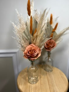 two vases with flowers and feathers on a table