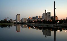 the city skyline is reflected in the water at dusk, with skyscrapers and other tall buildings on either side