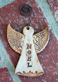 an angel ornament with the word noel written on it's side hanging from a hook