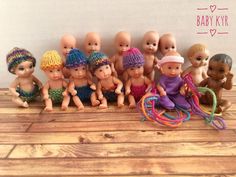 a group of baby dolls sitting next to each other on top of a wooden floor