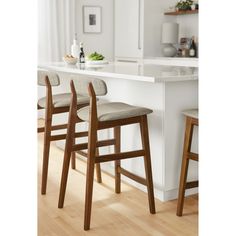 three wooden stools sitting in front of a kitchen counter