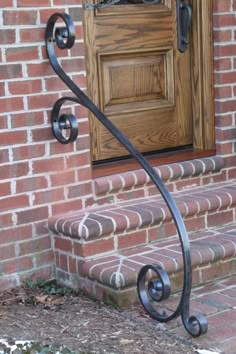 an iron handrail on the front steps of a brick building with a wooden door