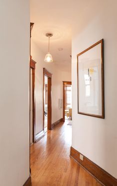 an empty hallway with wood floors and white walls