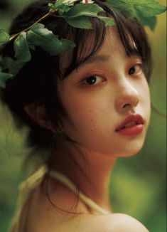 a young woman with a flower in her hair and leaves on her head is staring into the distance