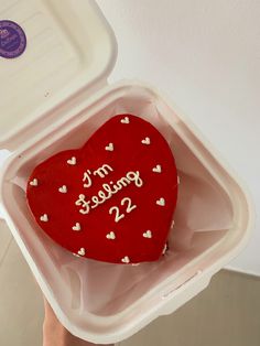 a red heart shaped cake in a foam container with writing on the inside and white hearts around it