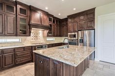 a large kitchen with marble counter tops and wooden cabinetry, along with stainless steel appliances