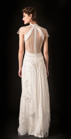 a woman in a long white dress with an open back and beading on it