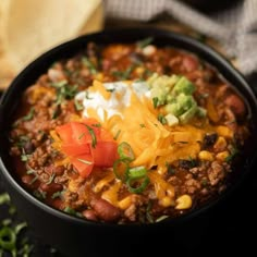 a black bowl filled with chili and cheese