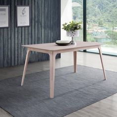 a wooden table with a bowl on top of it in front of a large window