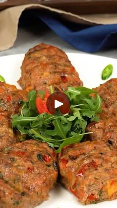 a white plate topped with meat patties covered in lettuce and tomato sauce