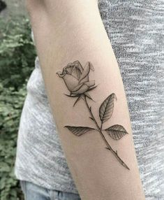 a woman's arm with a single rose tattoo on the left side of her arm