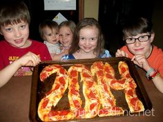 four children are posing in front of a birthday cake