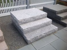 three stone steps sitting next to each other in front of a white picketed fence