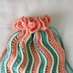 a crocheted drawstring bag sitting on top of a bed