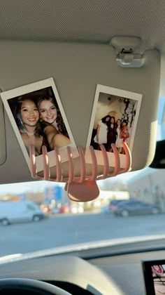 the interior of a car with two pictures hanging from it's dash board and on top of the dashboard