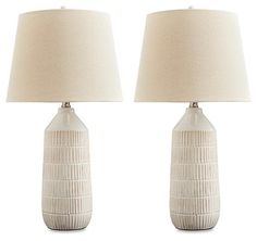 two white ceramic lamps with beige shades on each lamp and one is turned off to the side