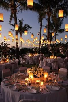 an image of a table set up for a wedding with paper lanterns in the sky