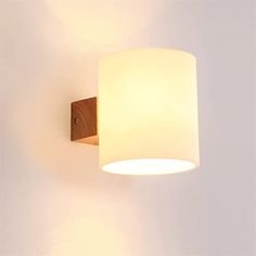 a light fixture mounted on the side of a white wall next to a wooden frame