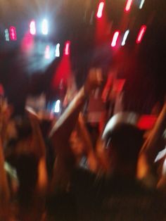 blurry image of people dancing at a concert with their hands up in the air