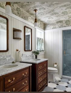 a bathroom with two sinks, a toilet and a walk in shower next to a tiled floor