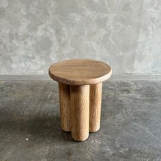 two wooden stools sitting on top of a cement floor next to a concrete wall