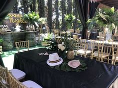 a table with chairs and tables covered in black cloths, plants and pineapples