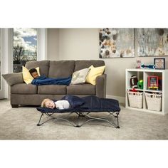 a young boy laying on top of a black chair in front of a brown couch