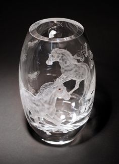 a clear glass vase with a white horse on it