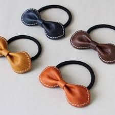 four different types of bow hair ties on white table with black and brown leather bows