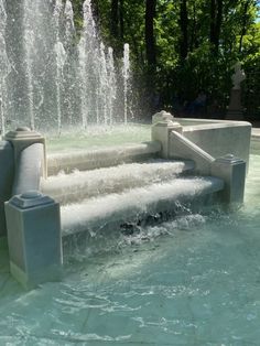 an outdoor fountain with water spouting from it's sides and benches in the middle