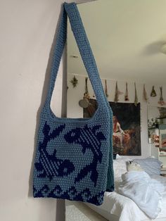 a blue purse hanging from the side of a wall next to a bed and mirror